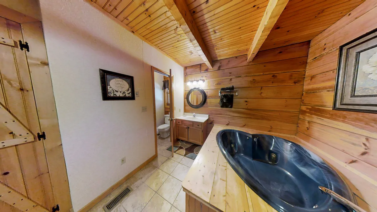 A tranquil ensuite bathroom featuring a freestanding bathtub, wooden accents, a modern sink area, and a large mirror. The spa-like ambiance invites relaxation and self-care.