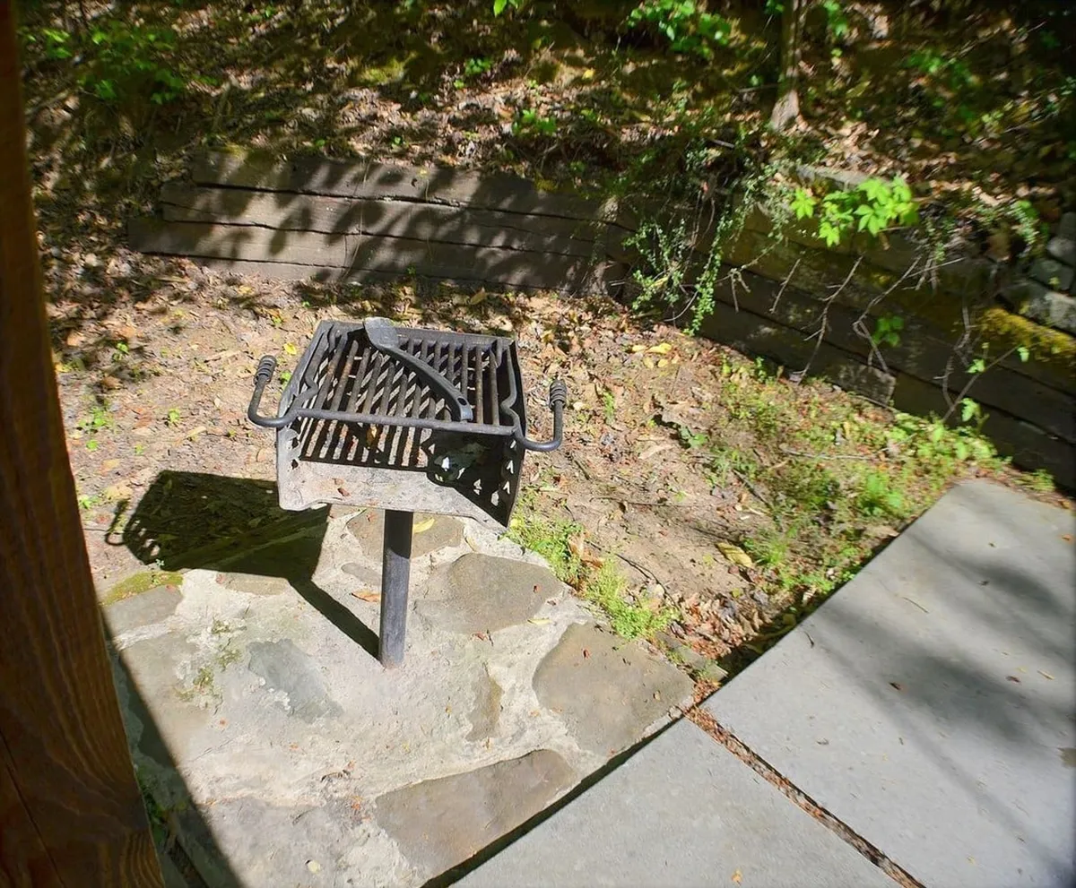 This exterior shot showcases a grill set amidst lush greenery and a stone pathway, hinting at outdoor dining possibilities. The setting is casual yet inviting, perfect for gatherings and alfresco meals as described in the section content.