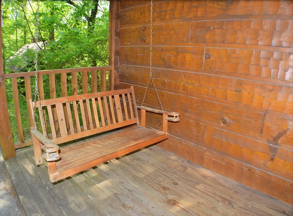 This image showcases a classic wooden porch swing set against warm wood-paneled walls and flooring, evoking a sense of tranquility. The inviting setting suggests a perfect spot for sipping morning coffee or enjoying the sunset while being surrounded by nature.